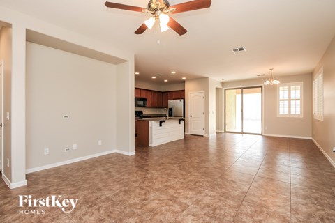 A spacious living room with a ceiling fan and lighting fixture.