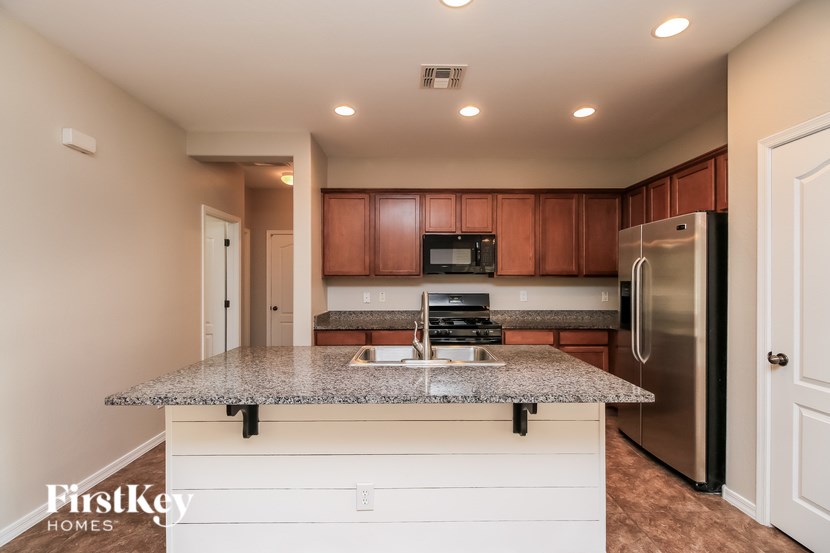 A kitchen with a granite countertop and wooden cabinets.