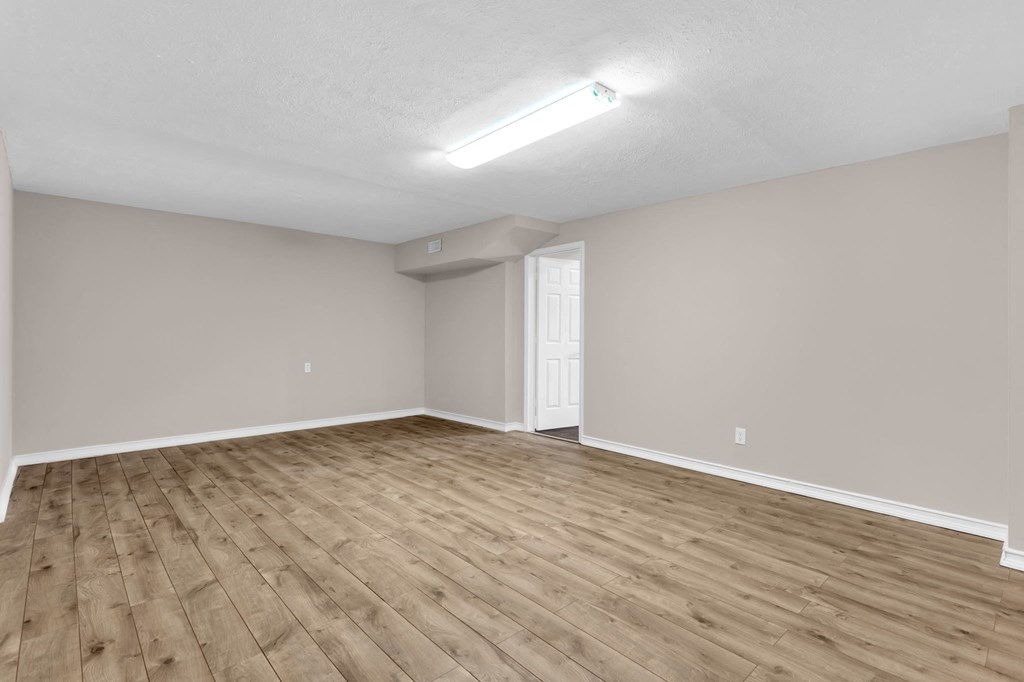an empty living room with wood flooring and a white door