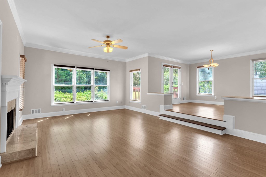 an empty living room with wood floors and a ceiling fan
