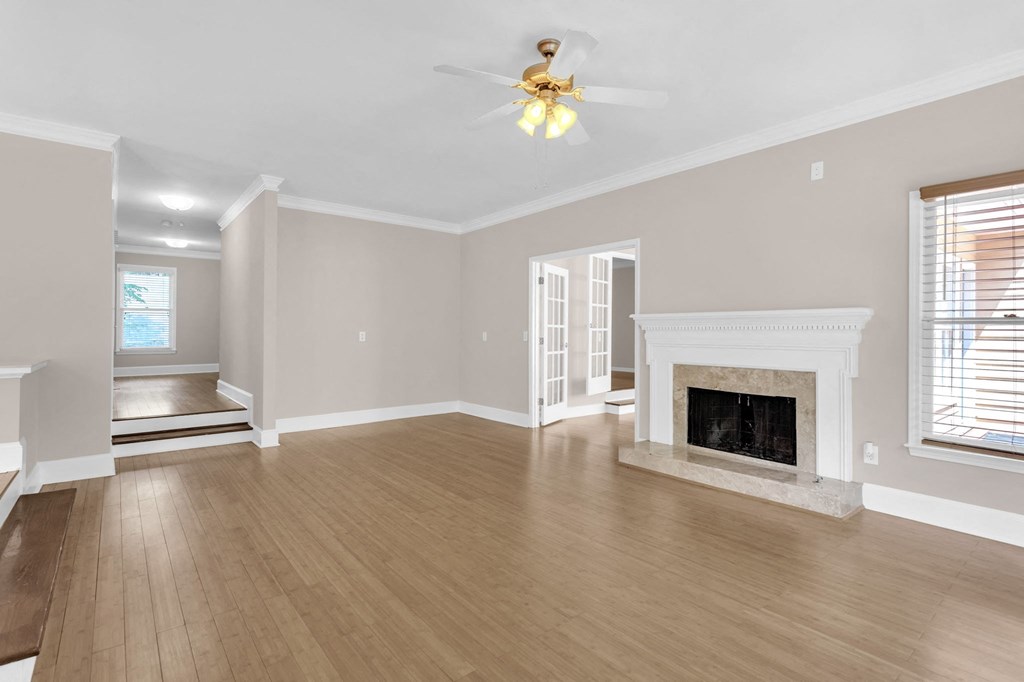 an empty living room with a fireplace and a ceiling fan