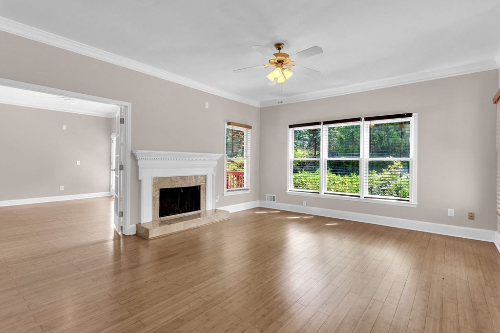 an empty living room with a fireplace and a ceiling fan
