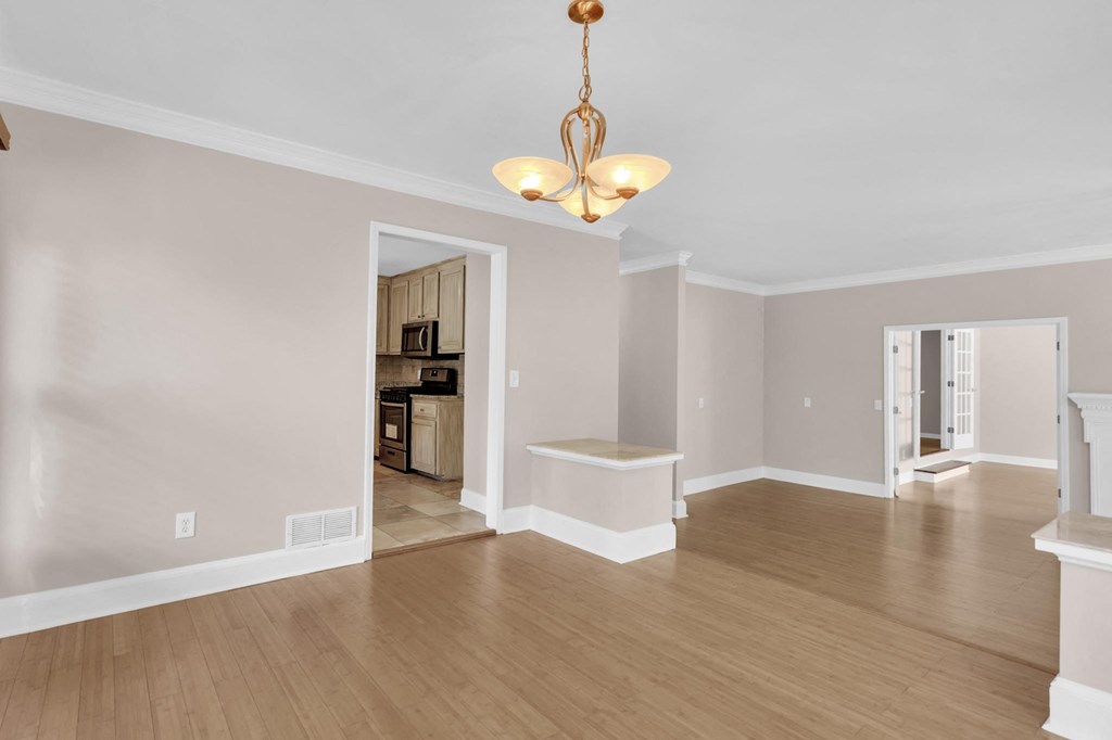 a dining room and living room with hard wood floors and a chandelier