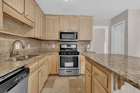 a kitchen with wooden cabinets and appliances and granite counter tops
