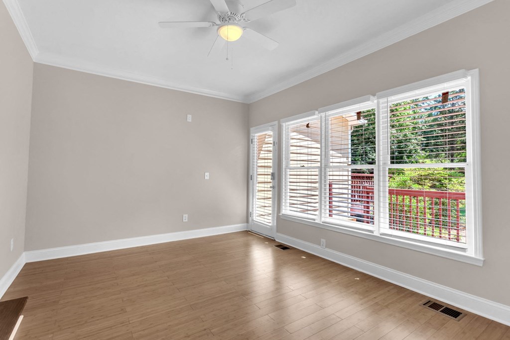 an empty living room with large windows and a ceiling fan