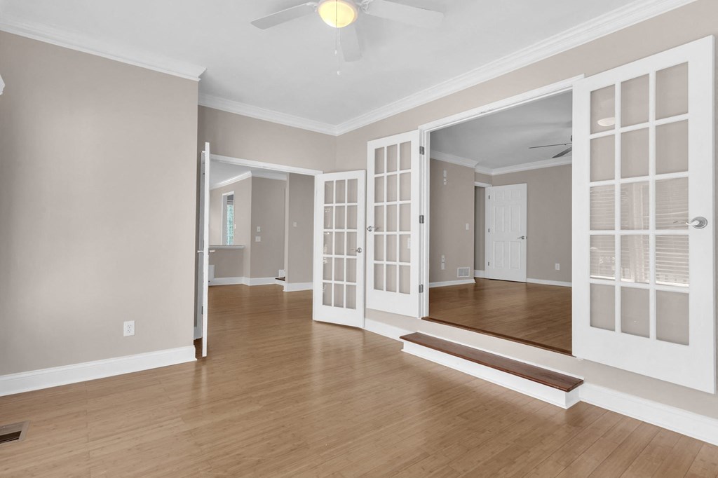an empty living room with hardwood floors and a ceiling fan