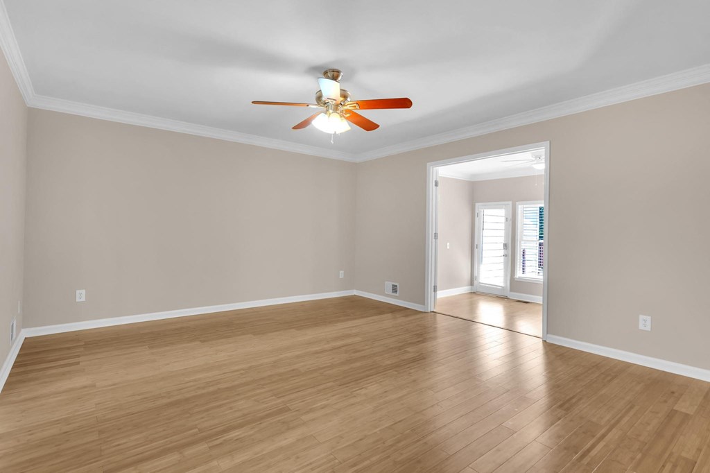 an empty living room with wood floors and a ceiling fan