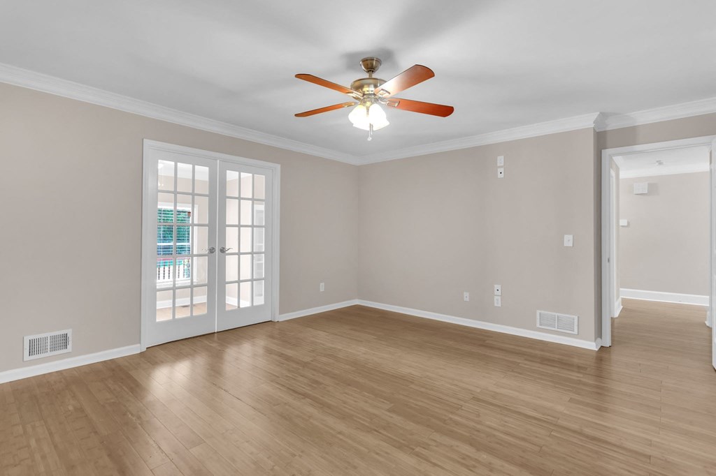 the living room of an empty home with a ceiling fan