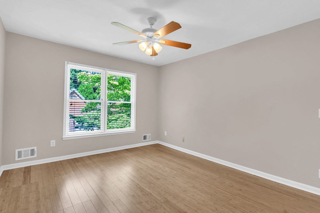 an empty living room with a ceiling fan and a window
