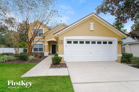 a yellow house with a white driveway and a white garage door