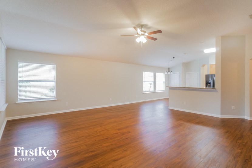 an empty living room with wood floors and a ceiling fan