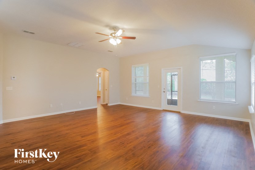 an empty living room with wood floors and a ceiling fan