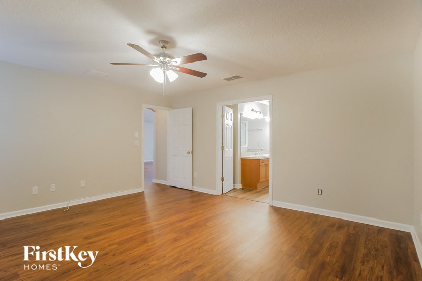 an empty living room with wood floors and a ceiling fan