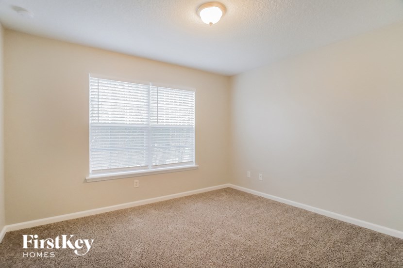 the spacious upstairs bedroom with carpet and a large window