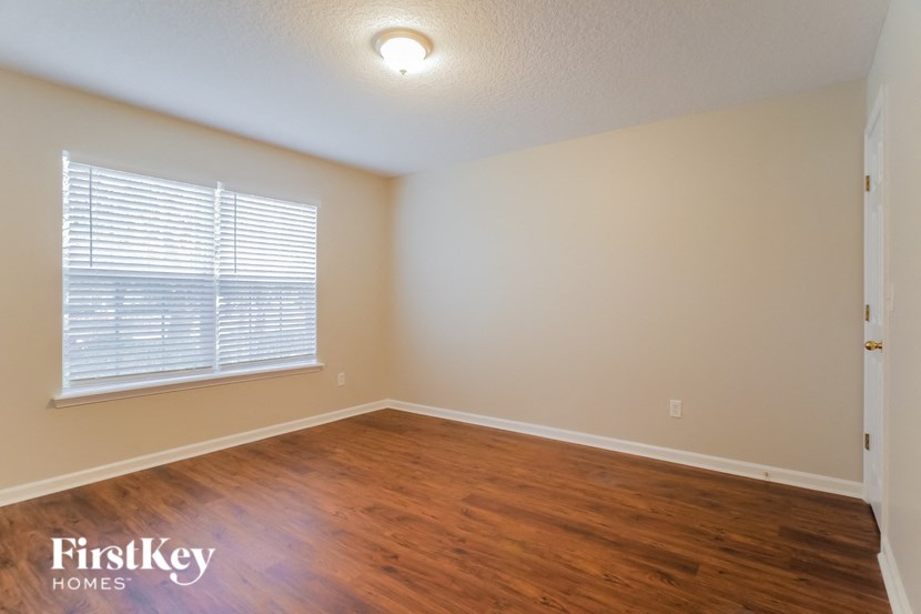 a bedroom with wood flooring and a window