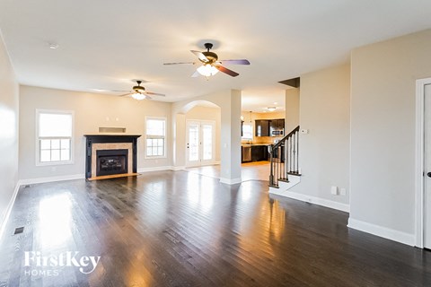 A spacious living room with a fireplace and a ceiling fan.