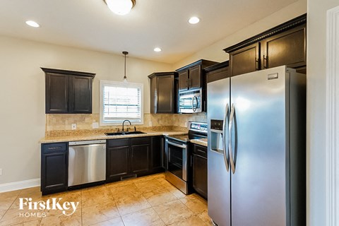 A kitchen with a refrigerator, sink, and cabinets.