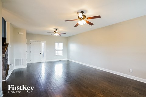 A spacious room with a ceiling fan and hardwood floors.