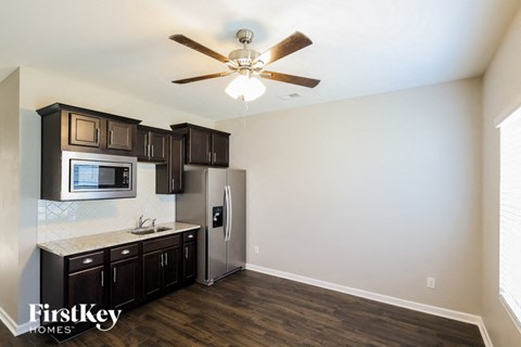 A kitchen with a refrigerator, microwave, and cabinets.