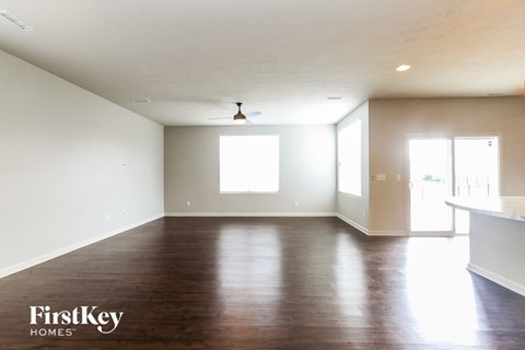 A spacious room with wooden flooring and a ceiling fan.