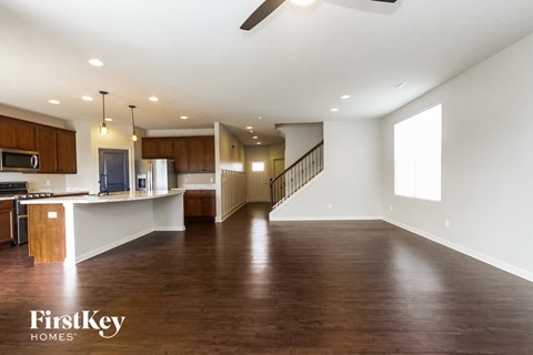 A spacious kitchen and living room with wooden floors and a staircase.
