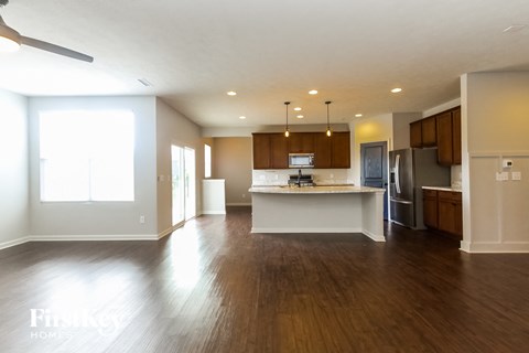 A spacious kitchen with wooden floors and a ceiling fan.