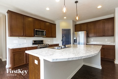 A kitchen with a marble countertop and wooden cabinets.