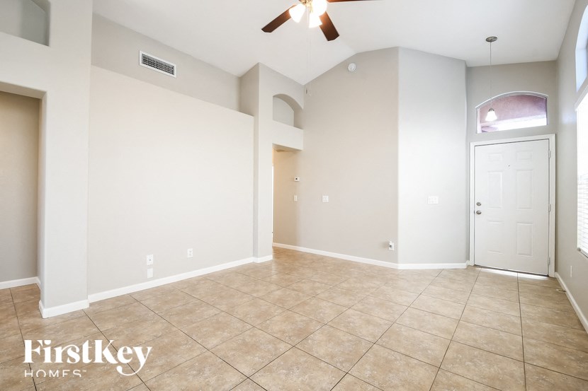 a empty living room with a ceiling fan and a door