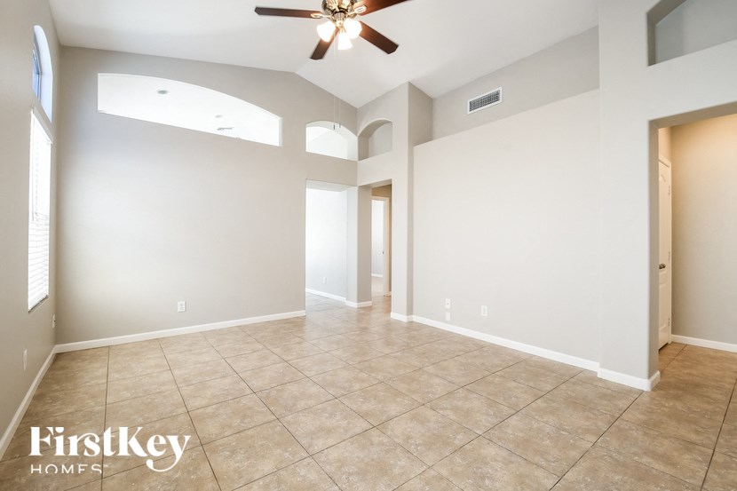 an empty living room with a ceiling fan and a tile floor