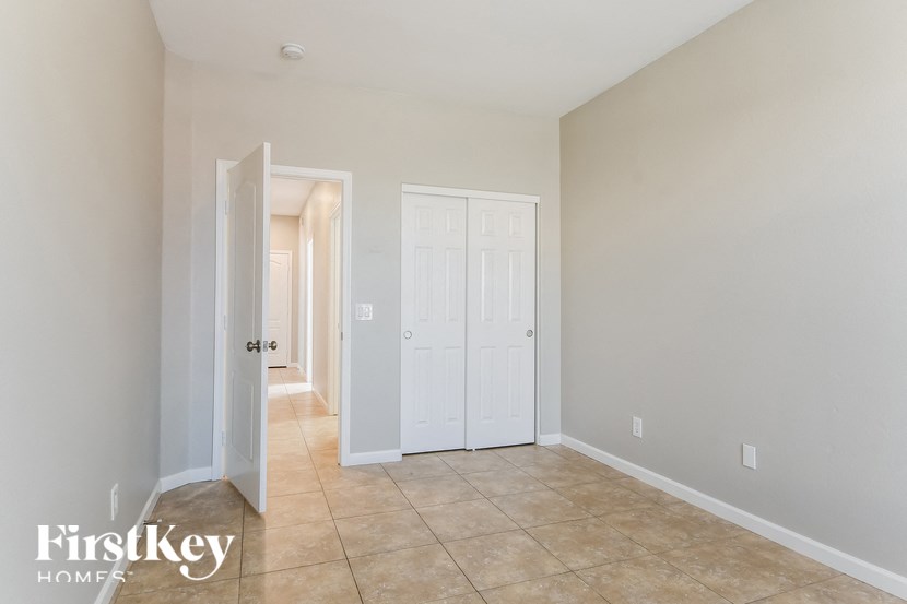 a tiled room with two closets and a door into a hallway