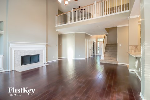 A spacious living room with a fireplace and wooden floors.