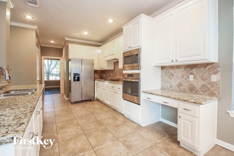 A kitchen with a granite counter top and white cabinets.