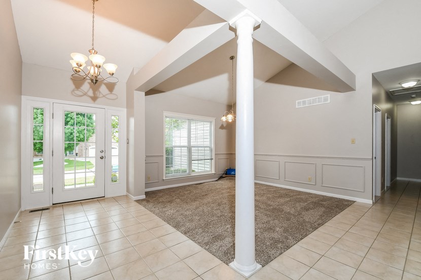 a large empty living room with white pillars and doors