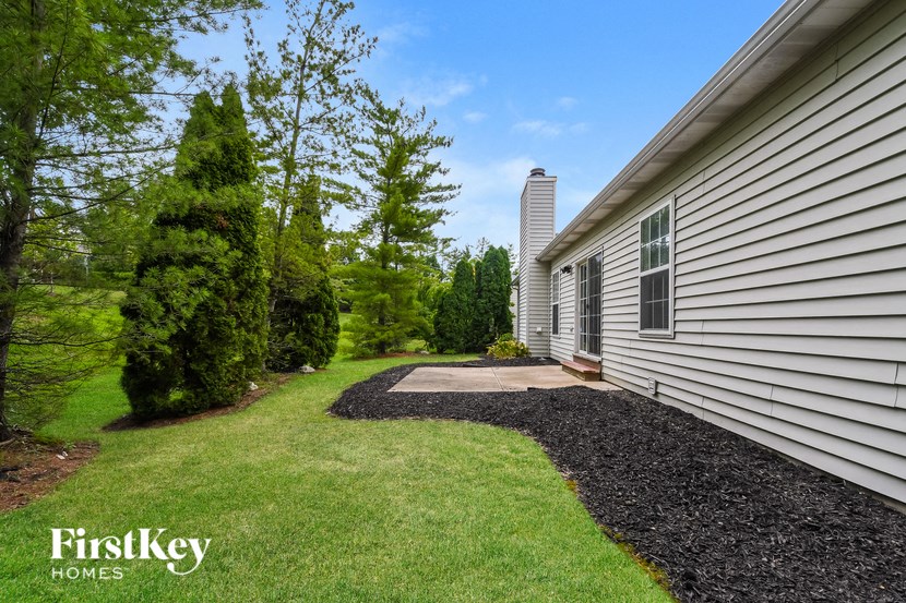 a side view of a house with a gravel driveway and grass