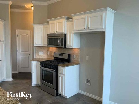 A kitchen with a black stove top oven and white cabinets.