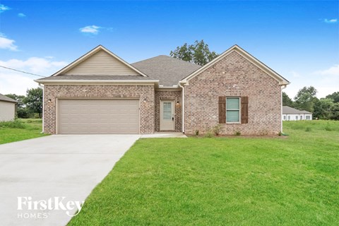 a brick house with a garage and a green lawn