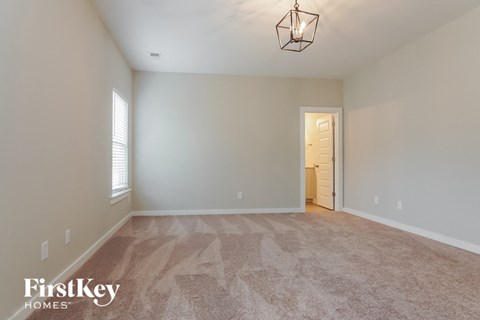 a spacious living room with carpet and a door to the hallway