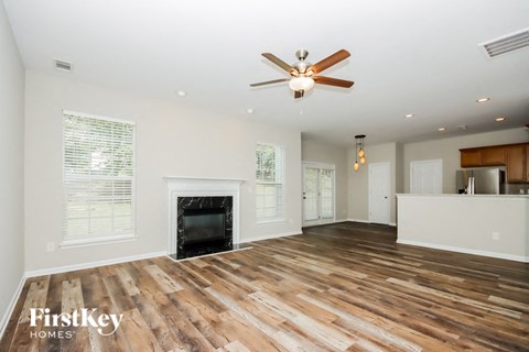 A spacious room with wooden flooring and a fireplace.