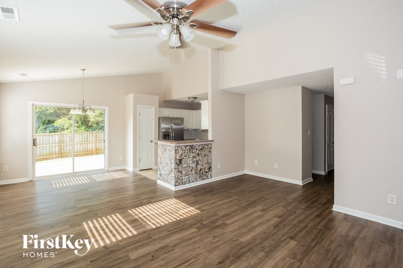 an empty living room and kitchen with a ceiling fan