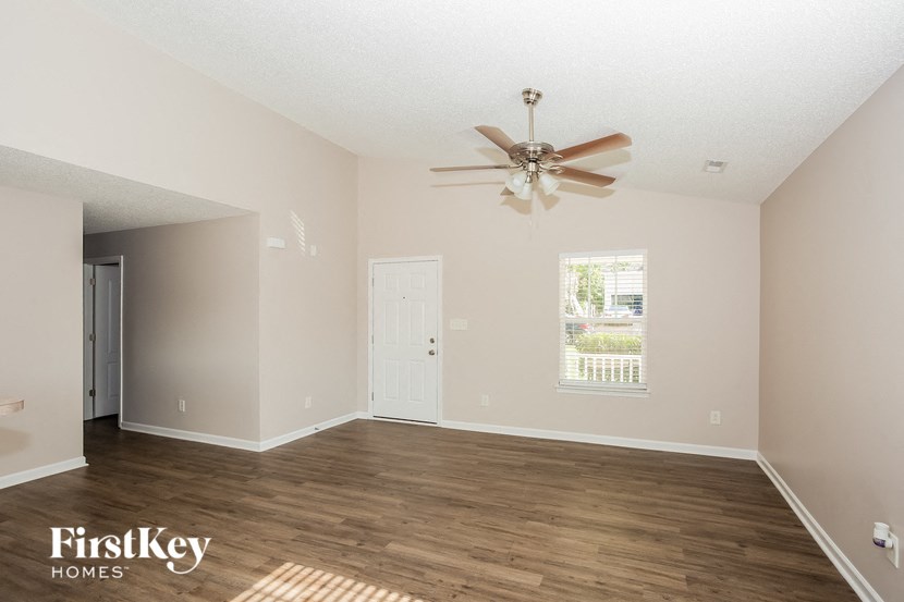 the living room of an empty house with a ceiling fan