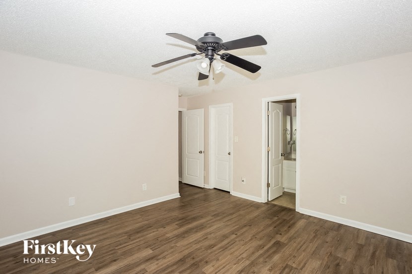 a living room with a ceiling fan and a door to a bathroom