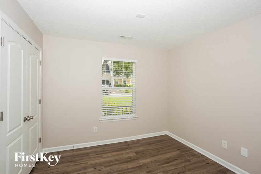 the living room of a home with a window and wooden floors