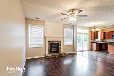 an empty living room with a fireplace and a ceiling fan