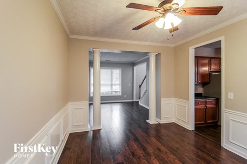 an empty living room with wood floors and a ceiling fan