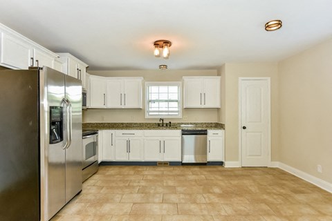 A kitchen with white cabinets and a tile floor.