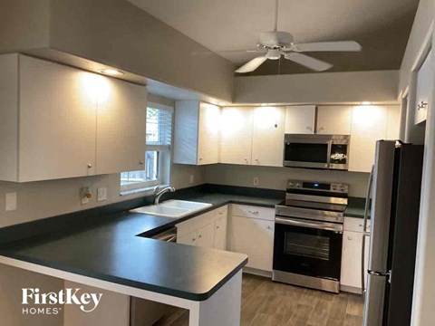 A kitchen with a black counter top and white cabinets.