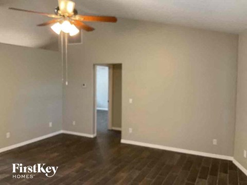 A room with a ceiling fan and wooden floors.