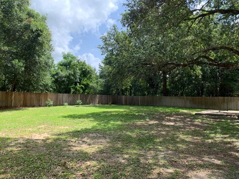 a backyard with a fence and grass and trees