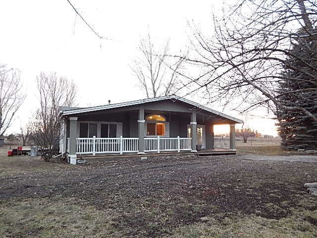 a small white house with a porch and a tree