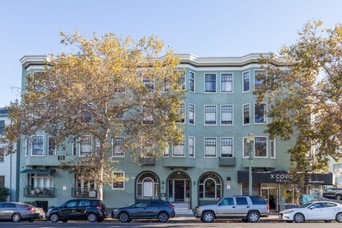 A street view of a building with cars parked in front.